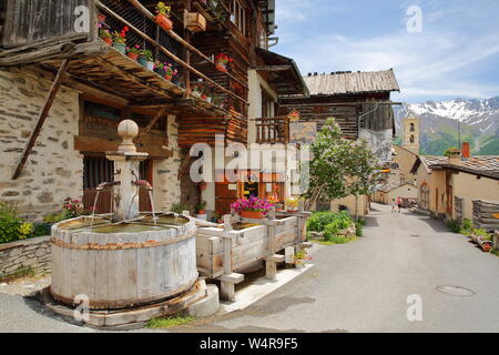 Traditionelle Holzhäuser, eine traditionelle Brunnen und die Kirche in Saint Veran Dorf, im Regionalen Naturpark Queyras, Südliche Alpen, Frankreich Stockfoto
