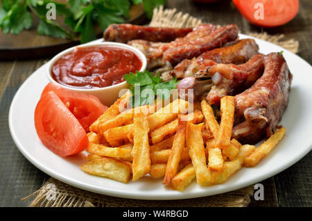 Kartoffel Pommes, Rippchen und Tomatensauce auf weiße Platte, Ansicht schließen Stockfoto