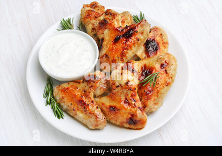 Gebackene Chicken Wings mit Soße auf weiße Platte Stockfoto