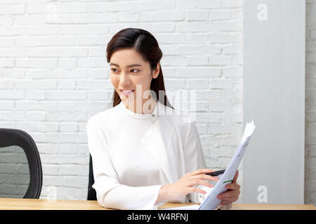 Frau sitzt hinter dem Schreibtisch im Büro, Peking, China Stockfoto