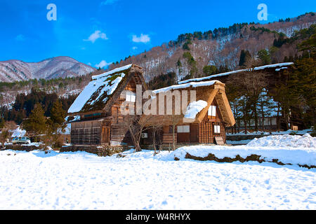 Holz- Häuser mit Strohdach mit Berg am Horizont im Winter, Shirakawa Dorf, Ono, Präfektur Gifu Stockfoto