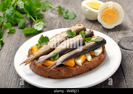 Sandwich mit Sprotten und Ei auf weiße Platte, Nahaufnahme Stockfoto