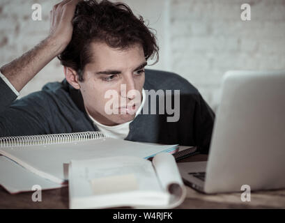Überarbeitet und müde männliche Kursteilnehmer spät in der Nacht arbeiten am Laptop versuchen nicht zu schlafen Gefühl ermüdet, besorgt und traurig. Moody Dark Light. Endg. Stockfoto