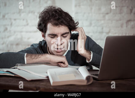 Überarbeitet und müde männliche Kursteilnehmer spät in der Nacht arbeiten am Laptop versuchen nicht zu schlafen Gefühl ermüdet, besorgt und traurig. Moody Dark Light. Endg. Stockfoto