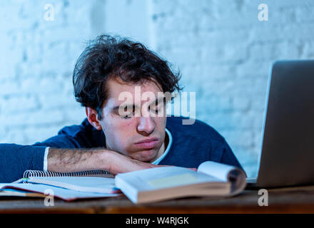 Überarbeitet und müde männliche Kursteilnehmer spät in der Nacht arbeiten am Laptop versuchen nicht zu schlafen Gefühl ermüdet, besorgt und traurig. Moody Dark Light. Endg. Stockfoto