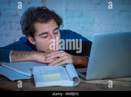 Überarbeitet und müde männliche Kursteilnehmer spät in der Nacht arbeiten am Laptop versuchen nicht zu schlafen Gefühl ermüdet, besorgt und traurig. Moody Dark Light. Endg. Stockfoto