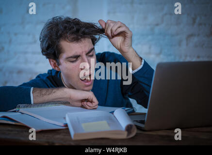 Überarbeitet und müde männliche Kursteilnehmer spät in der Nacht arbeiten am Laptop versuchen nicht zu schlafen Gefühl ermüdet, besorgt und traurig. Moody Dark Light. Endg. Stockfoto