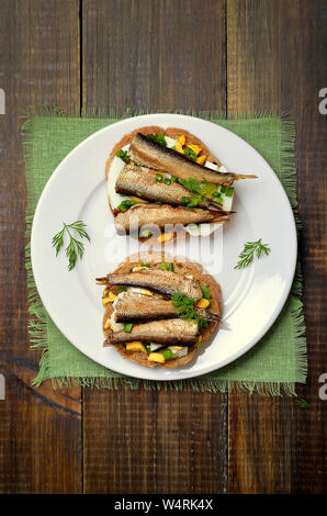 Appetitliche Sandwiches mit Sprotten und Ei auf weiße Platte, Ansicht von oben Stockfoto