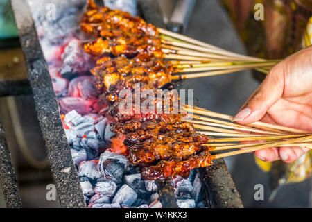 Hand der Person kochen Lamm shashliks über Grill, Ubud, Bali, Indonesien Stockfoto