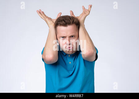 Mann mit Hörnern Geste auf dem Kopf und Kamera Stockfoto