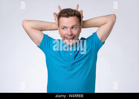 Mann mit Hörnern Geste auf dem Kopf und Kamera Stockfoto