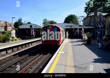 Eine U-Bahn kommt in Kew Gardens Eisenbahn- und U-Bahnstation London England UK an einem sonnigen Sommertag Stockfoto