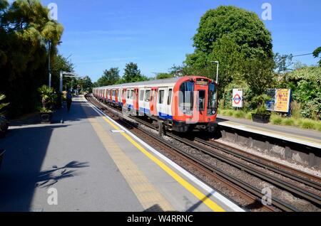 Eine U-Bahn kommt in Kew Gardens Eisenbahn- und U-Bahnstation London England UK an einem sonnigen Sommertag Stockfoto