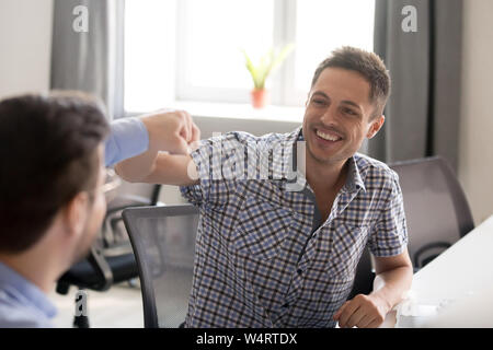 Lächelnde Menschen Faust stoßen mit Kollegen am Arbeitsplatz Stockfoto