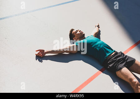 Mixed Race Sportler Festlegung auf der Laufstrecke und breitete die Arme im Sonnenlicht Stockfoto