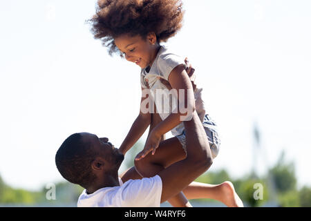 Happy afrikanischen Vater anheben Tochter Spaß zusammen haben im Freien Stockfoto