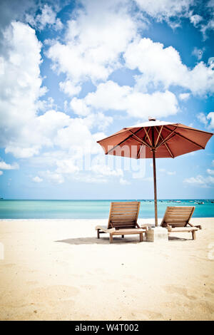 Zwei Liegestühle und ein Sonnenschirm am Strand, Strand Jimbaran, Bali. Indonesien Stockfoto