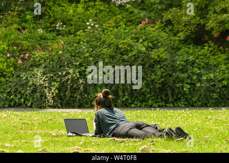 CARDIFF, WALES - Juli 2019: Schüler liegen auf Gras in einem öffentlichen Park in Cardiff in diesem Notebook Computer. Stockfoto