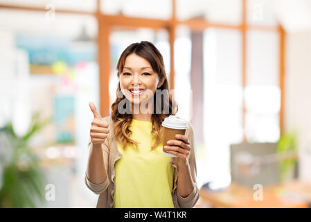 Asiatische Frau trinkt Kaffee und zeigen Daumen hoch Stockfoto
