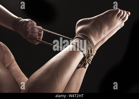 Devote Frau in Hog Tie Bondage Position auf schwarzem Hintergrund/BDSM  Thema Stockfotografie