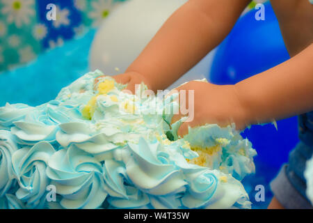 Eine nicht erkennbare Kind smashing Geburtstag Kuchen mit Händen. Geburtstag Kuchen smash durch kleine Zicklein Konzept. Stockfoto