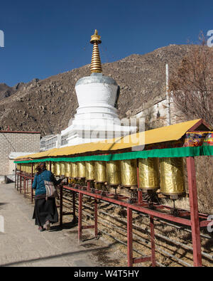 China, Tibet, Lhasa, ein Anbeter spins Gebetsmühlen vor einer Stupa in dem buddhistischen Kloster Drepung, die in 1416 AD gegründet und war das größte Kloster in Tibet Gehäuse bis zu 10 000 Mönche. Stockfoto