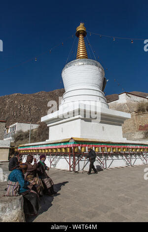 China, Tibet, Lhasa, Frauen sitzen vor dem Gebet Rädern um ein Stupa im buddhistischen Kloster Drepung, 1416 AD gegründet und war das größte Kloster in Tibet Gehäuse bis zu 10 000 Mönche. Stockfoto