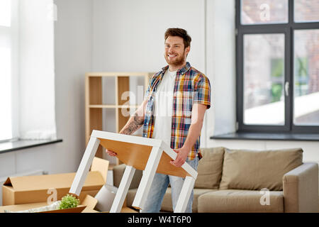 Glückliche Menschen mit Tisch zum neuen Haus bewegen Stockfoto