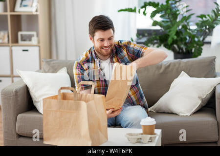 Lächelnd Mann auspacken Essen zum Mitnehmen zu Hause Stockfoto