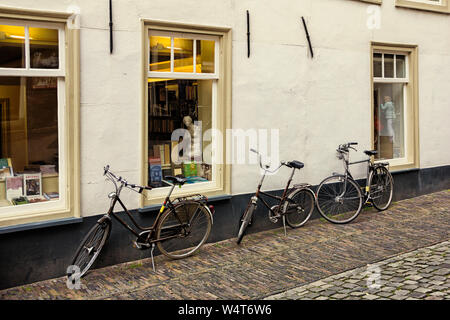 Leiden, Holland, Niederlande, 17. April 2019. Üblichen Straße und Book Shop windows Ansicht mit einer Kopie der Venus Statue, traditionelle Häuser und abgestellte Fahrräder Stockfoto