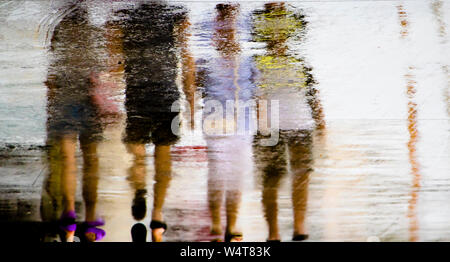 Blurry abstrakte Reflexion Silhouette in eine Pfütze von Menschen zu Fuß an einem regnerischen Sommertag Stockfoto