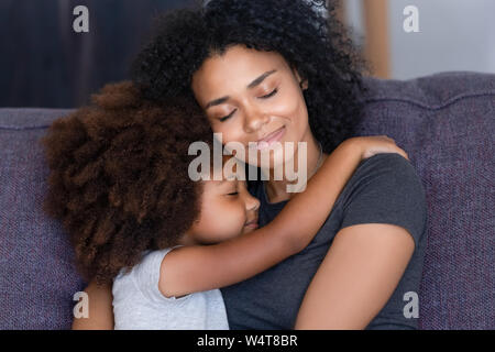 Closeup afrikanischen Tochter umarmen Mutter sitzen auf der Couch zu Hause Stockfoto