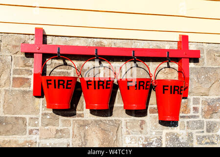 Vier rote Feuer Eimer von Haken an einem stillgelegten Bahnhof Stellwerk auf der Tarka Trail in Instow, Devon, Großbritannien ausgesetzt Stockfoto