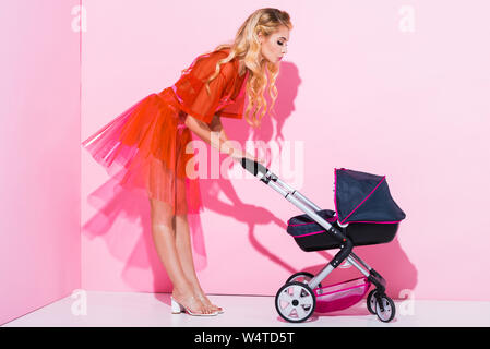 Schöne Mädchen mit Kinderwagen schmollen, Lippen auf Rosa, Puppe Konzept Stockfoto