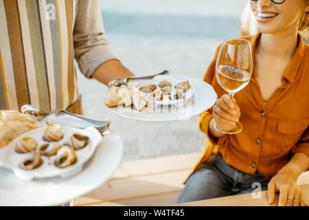 Kellner serviert köstliche Gerichte mit Schnecken und Brot zu eine Frau im Restaurant gefüllt, Nahaufnahme Stockfoto