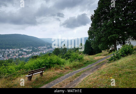 Bad Orb, Deutschland - Juli 13, 2019: Ein Blick von der Mollkenberg Hill im Spessart auf das Stadtbild von Bad Orb mit einer leeren Bank im Vordergrund. Stockfoto