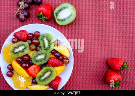 Gesunde vegetarische Frisches Obst Sommer Salat Dessert mit Orangen, Erdbeeren, Kiwi Pfirsiche und Trauben Stockfoto