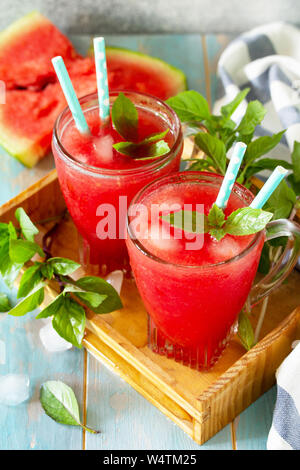 Kalte Wassermelone Smoothie. Sommer Wassermelonen trinken in Gläsern und Scheiben Wassermelone auf rustikalen Holztisch. Stockfoto