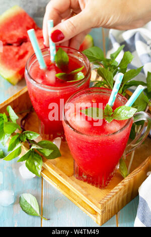 Kalte Wassermelone Smoothie. Sommer Wassermelonen trinken in Gläsern und Scheiben Wassermelone auf rustikalen Holztisch. Stockfoto