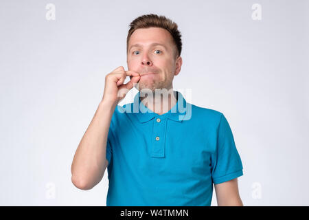 Junger Mann schließen Mund und Lippen als zip mit den Fingern. Stockfoto