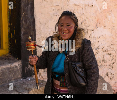 China, Tibet, Lhasa, eine junge tibetische Frau Pilgrim mit ihrem Gebet Rad im Kloster Drepung. Stockfoto