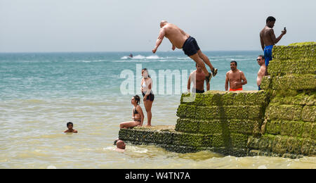 Brighton UK 25. Juli 2019 - Junge Männer tauchen Sie ein in das Meer (bekannt als grabsteineffekt) von einem groyne am Brighton Beach als Besucher einen anderen heißen, sonnigen Tag in Großbritannien genießen mit meteorologen Vorhersagen Rekordtemperaturen für Teile des Südostens. Foto: Simon Dack/Alamy leben Nachrichten Stockfoto