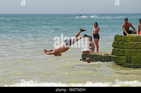 Brighton UK 25. Juli 2019 - Junge Männer tauchen Sie ein in das Meer (bekannt als grabsteineffekt) von einem groyne am Brighton Beach als Besucher einen anderen heißen, sonnigen Tag in Großbritannien genießen mit meteorologen Vorhersagen Rekordtemperaturen für Teile des Südostens. Foto: Simon Dack/Alamy leben Nachrichten Stockfoto