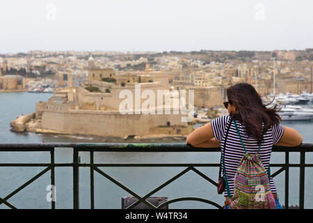 Weibliche Touristen mit dunklen Haaren auf Fort St. Angelo in der Ferne. Stockfoto