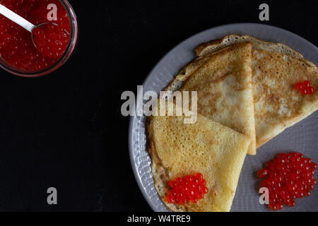 Blini Dreiecke oder Crepes mit rotem Kaviar auf der Platte mit Jar Stockfoto