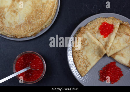 Blini Dreiecke oder Crepes mit rotem Kaviar auf der Platte mit Jar Stockfoto