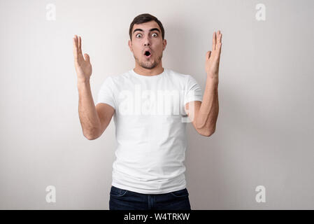 Portrait von schockiert, überrascht, junger Kerl zeigt Hände Größe in Weiß leer t-shirt Design. Stockfoto