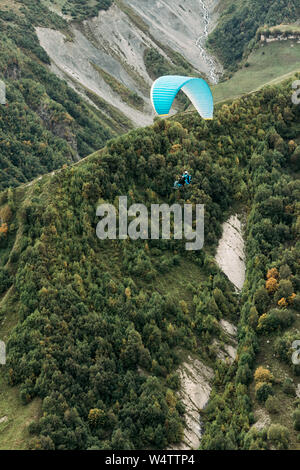 Gleitschirm fliegen über Berge an einem sonnigen Tag. Gleitschirmfliegen im Kaukasus Stockfoto