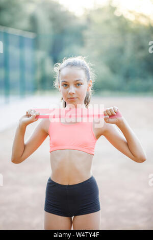 Eine junge, hübsche Mädchen von schlanken Körper, in einem Sport Uniform gekleidet, verbringt Zeit auf einem Sportplatz und führt körperliche Übungen. Lebensstil Stockfoto