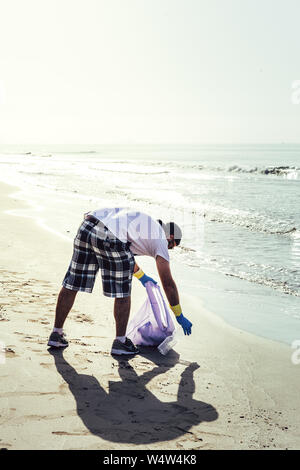 Mann Sammlung der Abfälle, die das Meer im Beutel verschmutzen, Menschen zu helfen, um die Natur sauber und Aufnehmen der Müll vom Ufer, freiwilliger Campaig Stockfoto